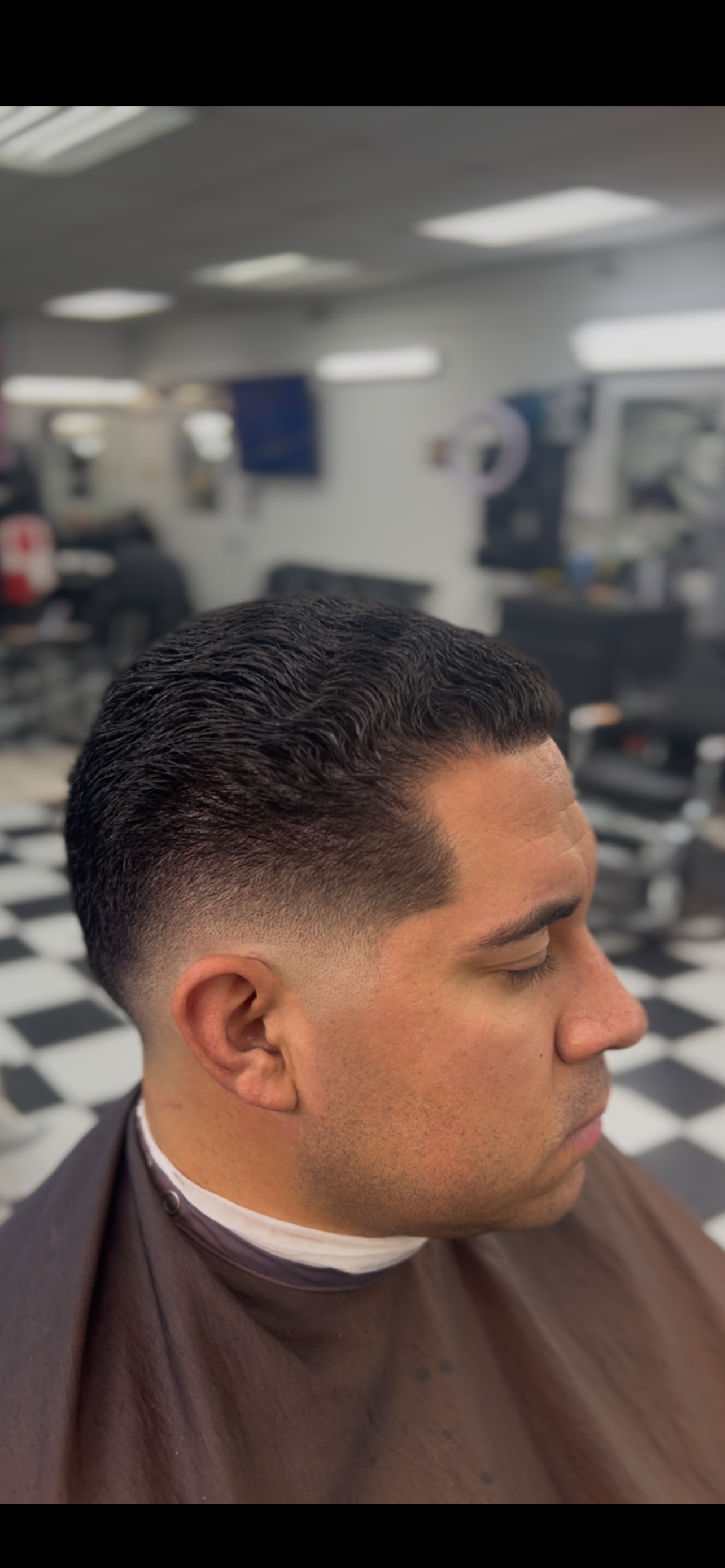 Barber giving a client a haircut at Super Natural Barbershop